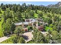 Scenic view of a large home with mature trees on a hillside with a driveway and a multi-car garage at 45 Bellevue Dr, Boulder, CO 80302