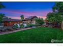 Spacious backyard with a lush lawn, garden beds, and a covered patio area perfect for outdoor living at 4900 W 6Th Ave, Denver, CO 80204