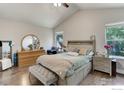 Well-lit bedroom features a comfortable bed, wood flooring, and a round mirror above a dresser at 647 Florence Ave, Firestone, CO 80520