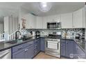 Stylish kitchen with stainless steel appliances, granite counters, and lovely blue backsplash at 647 Florence Ave, Firestone, CO 80520