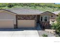 Charming home exterior featuring a stone facade, well-manicured landscaping, and a two-car garage at 6945 N Fargo Trl, Littleton, CO 80125
