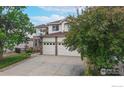 Two-story home with three car garage, lush landscaping, and a spacious driveway at 7597 Bison Ct, Littleton, CO 80125