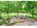Inviting backyard patio with stone fire pit and Adirondack chairs surrounded by mature trees and lush lawn at 8911 Little Raven Trl, Niwot, CO 80503