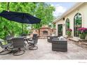 Elegant outdoor patio area with a stone fireplace, dining table, and comfortable seating at 8911 Little Raven Trl, Niwot, CO 80503
