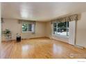 Bright living room with large windows, hardwood floors, and traditional-style curtains at 1133 Frontier Dr, Longmont, CO 80501