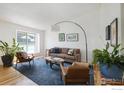 Open living room with a blue rug, hardwood floors, large windows and neutral decor at 137 S Polk Ave, Louisville, CO 80027