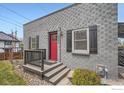 Charming home featuring a gray brick exterior, a red front door, and a welcoming front porch at 4009 W 52Nd Ave, Denver, CO 80212