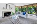 Bright living room with a cozy fireplace, neutral furniture, and expansive windows overlooking lush greenery at 525 13Th St, Boulder, CO 80302