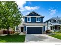 Charming two-story home features blue siding, a well-kept lawn, an attached garage, and manicured landscaping at 5609 Mount Sanitas Ave, Longmont, CO 80503