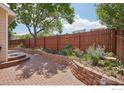 Brick patio with a retaining wall and a tall wooden fence, creating a private outdoor space at 7755 Halleys Dr, Littleton, CO 80125