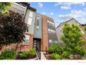 Multi-level modern townhome with brick and gray siding, complimented by well-maintained landscaping and a welcoming entrance at 9052 E 47Th Ave, Denver, CO 80238