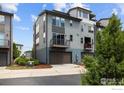 Modern townhome with gray siding, features a private balcony, an attached garage, and tidy landscaping at 9052 E 47Th Ave, Denver, CO 80238