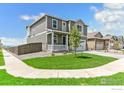 Well-maintained two-story home with gray siding, a covered porch, and green lawn, situated in a neighborhood at 955 Tallus St, Lochbuie, CO 80603
