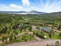 Scenic aerial view of the wooded property with lush greenery and mountain backdrop at 11997 Coal Creek Heights Dr, Golden, CO 80403