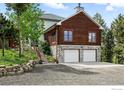 Charming home with log siding, stone accents, two-car garage, and landscaped entrance at 11997 Coal Creek Heights Dr, Golden, CO 80403