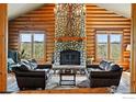 Comfortable living room featuring a stone fireplace, log walls, and natural light at 11997 Coal Creek Heights Dr, Golden, CO 80403