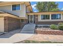 Close-up view of home's entrance with brick accents, concrete steps, and landscaped garden at 1951 S Deframe Way, Lakewood, CO 80228