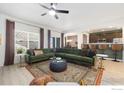 Spacious living room with green sectional, ceiling fan, and eat-in kitchen area with bar seating at 2483 Tabor St, Berthoud, CO 80513