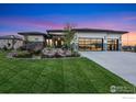 Modern home featuring a well-manicured lawn, landscaping and three car garage at 2659 Heron Lakes Pkwy, Berthoud, CO 80513