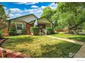 Beautiful front yard with a brick house, mature trees, and a well-maintained lawn at 301 E Colorado Ave, Berthoud, CO 80513