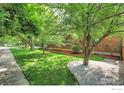 Lush side yard featuring mature trees, green grass, and a well-maintained brick exterior at 301 E Colorado Ave, Berthoud, CO 80513