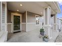 Inviting front porch with neutral tones, decorative columns, and charming potted plants at 858 Turpin Way, Erie, CO 80516
