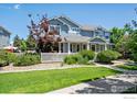 Beautiful two-story home with a lush lawn, white picket fence, and mature trees at 9273 W 107Th Pl, Broomfield, CO 80021