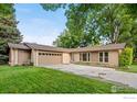 Charming single-story home with a well-manicured lawn, mature trees, and an attached garage at 11198 W 59Th Pl, Arvada, CO 80004