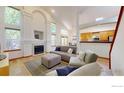 Bright living room with fireplace, vaulted ceilings, large windows, and access to kitchen and dining at 13673 Cook St, Thornton, CO 80602