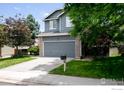 Beautiful two-story home with a gray exterior, green lawn, mature trees, and a two-car garage at 13836 Harrison Dr, Thornton, CO 80602