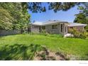 Expansive backyard with lush grass, mature trees, and a covered patio offering privacy at 1448 16Th Ave, Longmont, CO 80501