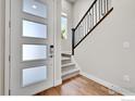 Welcoming foyer with staircase and modern front door with glass panels at 1575 W 68Th Ave, Denver, CO 80221