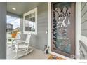 Inviting front porch featuring a decorative front door, rocking chairs, and a charming bear accent at 348 Vista Cliff Ct, Castle Rock, CO 80104