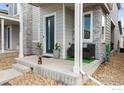 Inviting front porch with gray stone accents, a dark teal door, and stylish seating arrangement at 5325 Spalding Pl, Frederick, CO 80504