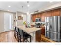 Stylish kitchen features stainless steel appliances, granite countertops, an island, and hardwood floors at 5325 Spalding Pl, Frederick, CO 80504