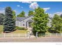 Beautiful home with gray siding, well-manicured lawn, mature trees, and white picket fence at 5753 Secrest Ct, Golden, CO 80403