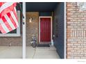 Close-up of the home's welcoming front entry with a brick facade and a vibrant red door at 629 Sumac St, Frederick, CO 80530