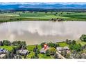 Stunning aerial view of lakefront property with mature trees and lake views in the background at 7975 Anchor Dr, Longmont, CO 80504