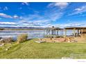Lakeside view featuring a private dock and fire pit, perfect for outdoor entertaining against a backdrop of serene waters and mountains at 7975 Anchor Dr, Longmont, CO 80504