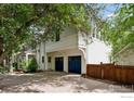 Attached two-car garage with blue doors and a side entrance, surrounded by lush trees at 877 Racquet Ln, Boulder, CO 80303