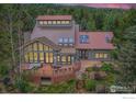 Stunning home boasts a metal roof, large deck, and walls of windows showcasing the forested surroundings at 148 Granite Dr, Boulder, CO 80302