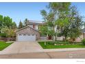 Charming two-story home with stone accents, solar panels, manicured lawn, and mature trees at 1616 Cedarwood Dr, Longmont, CO 80504