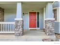 Inviting covered front porch with stone pillars and a bright red front door at 1616 Cedarwood Dr, Longmont, CO 80504