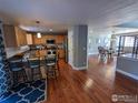 Spacious kitchen featuring granite countertops, stainless steel appliances, wood flooring, and breakfast bar with seating at 1616 Cedarwood Dr, Longmont, CO 80504