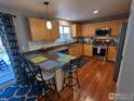 Well-appointed kitchen boasts stainless appliances, wood cabinets, breakfast bar and hardwood floors at 1616 Cedarwood Dr, Longmont, CO 80504