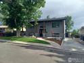 Well-maintained grey brick home with dark trim and a landscaped front yard and long driveway at 1843 Spruce Ave, Longmont, CO 80501
