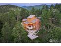 Aerial view of a home with a deck, stone chimney and lush trees at 207 Kelly E Rd, Boulder, CO 80302