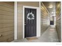 Front door with decorative wreath and sidelight is painted black with white trim in a condo hallway at 3045 Blue Sky Cir # 105, Erie, CO 80516