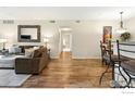 Open-concept living room with hardwood floors, neutral walls, and comfortable seating, with a dining area nearby at 3045 Blue Sky Cir # 105, Erie, CO 80516