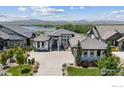 Aerial view of a modern home with professionally landscaped yard, lake views, and gray tile roof at 3095 Heron Lakes Pkwy, Berthoud, CO 80513